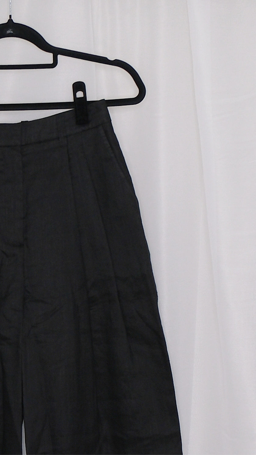 Black wide-leg pants on a hanger against a white background