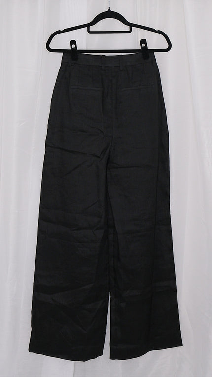 Black wide-leg pants on a hanger against a white background