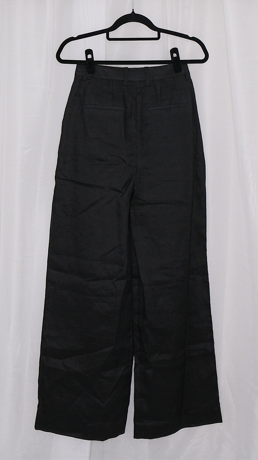 Black wide-leg pants on a hanger against a white background