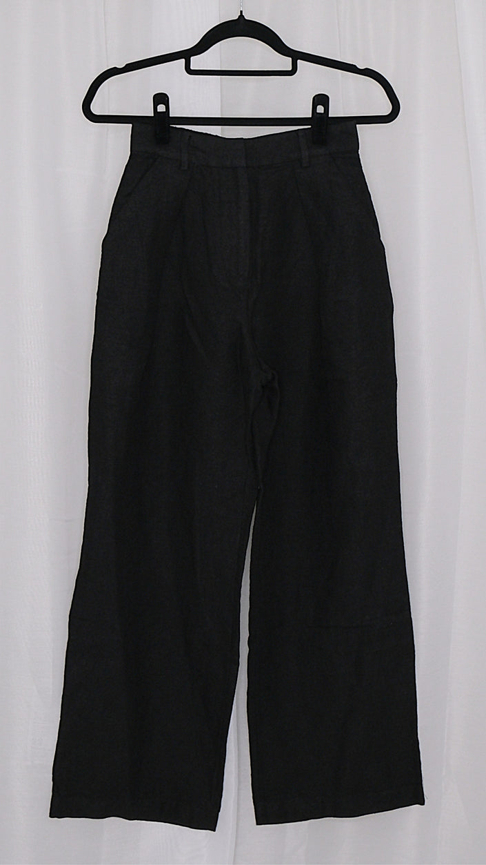 Black pants on a hanger against a white background