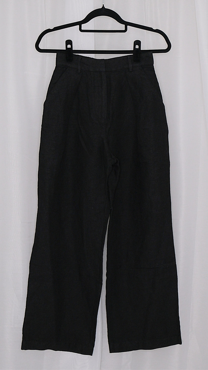 Black pants on a hanger against a white background