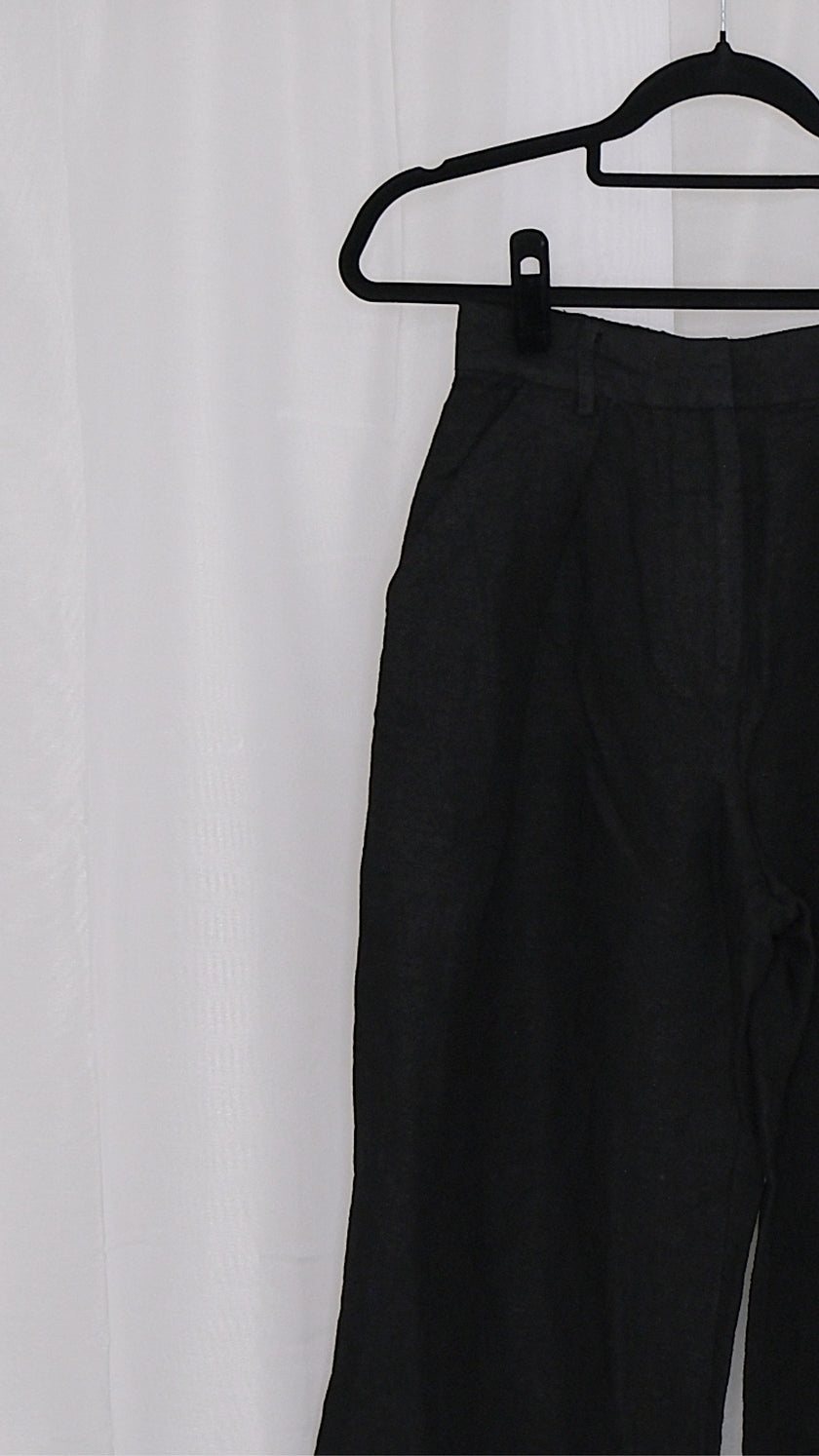 Black pants on a hanger against a white background