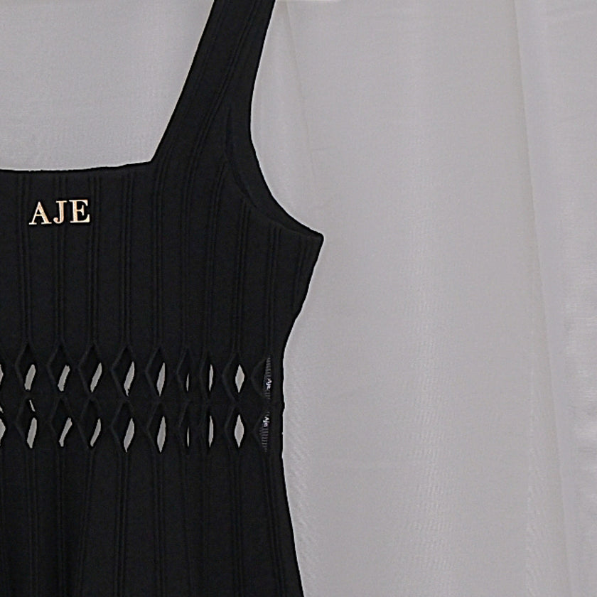 Black dress with cut-out details on a hanger against a white background